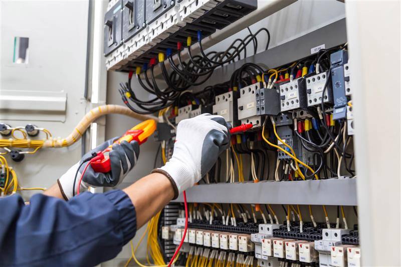 Electrician testing an industrial control panel